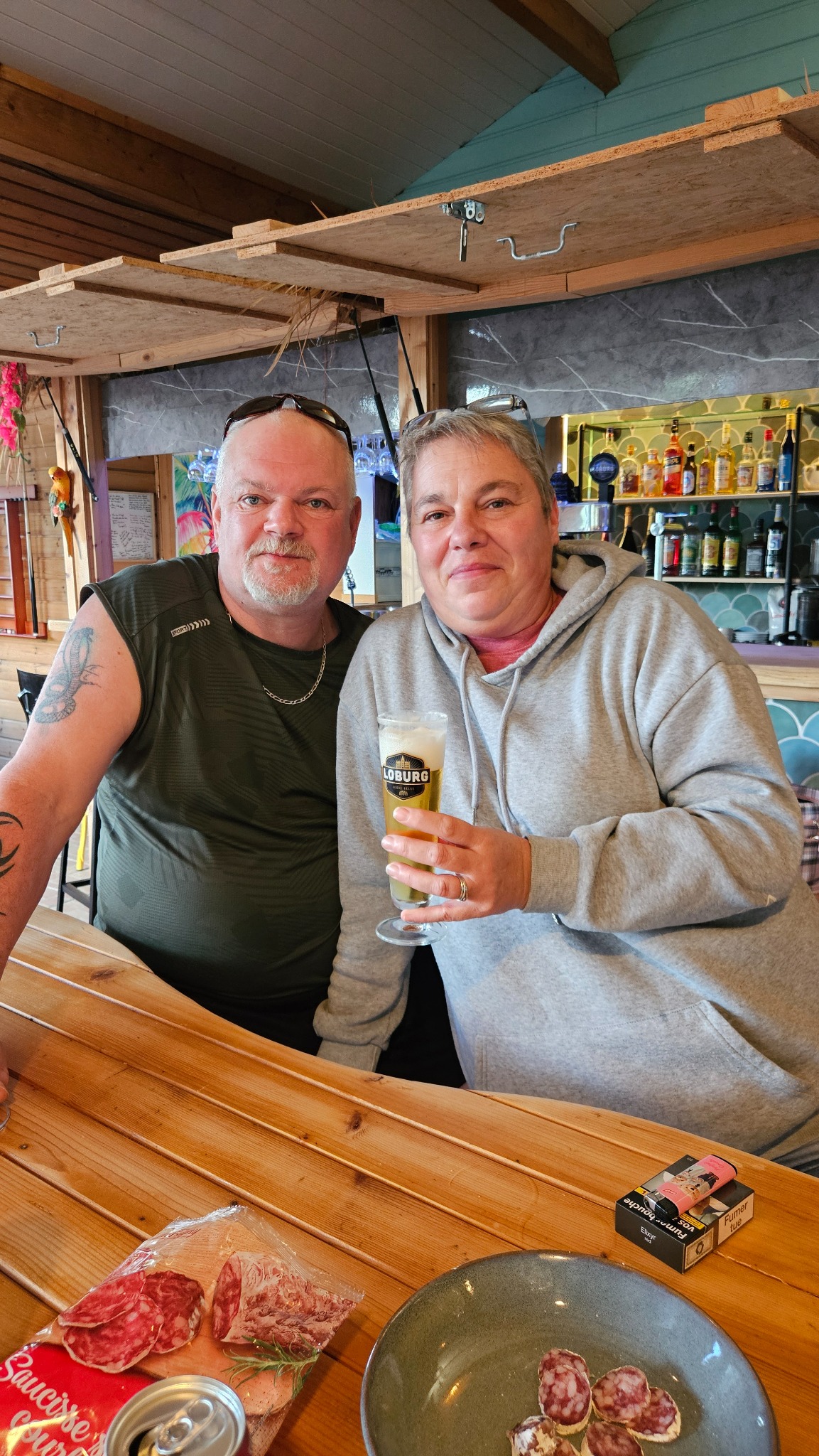 Deux personnes partagent un moment au comptoir du bar du Camping Ohana