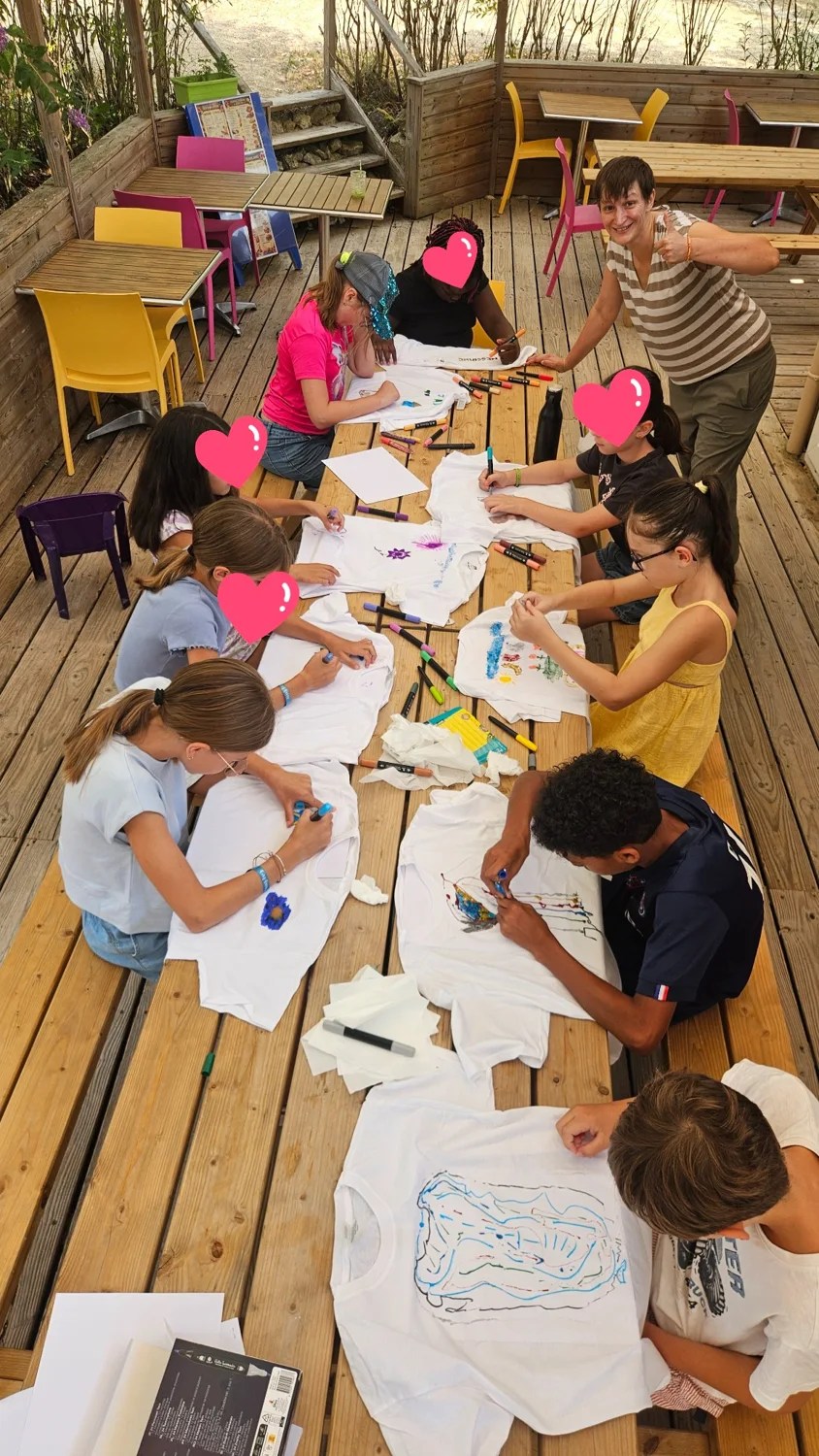 Les enfants dessinent et colorient ensemble autour d’une table au club enfants d’Ohana