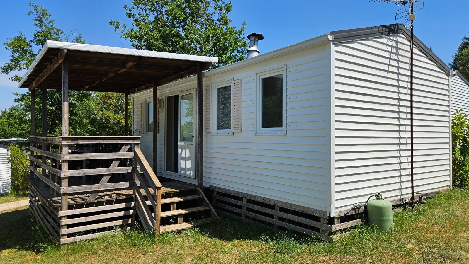 Mobil-home du Camping Ohana avec terrasse en bois, au soleil et près des arbres