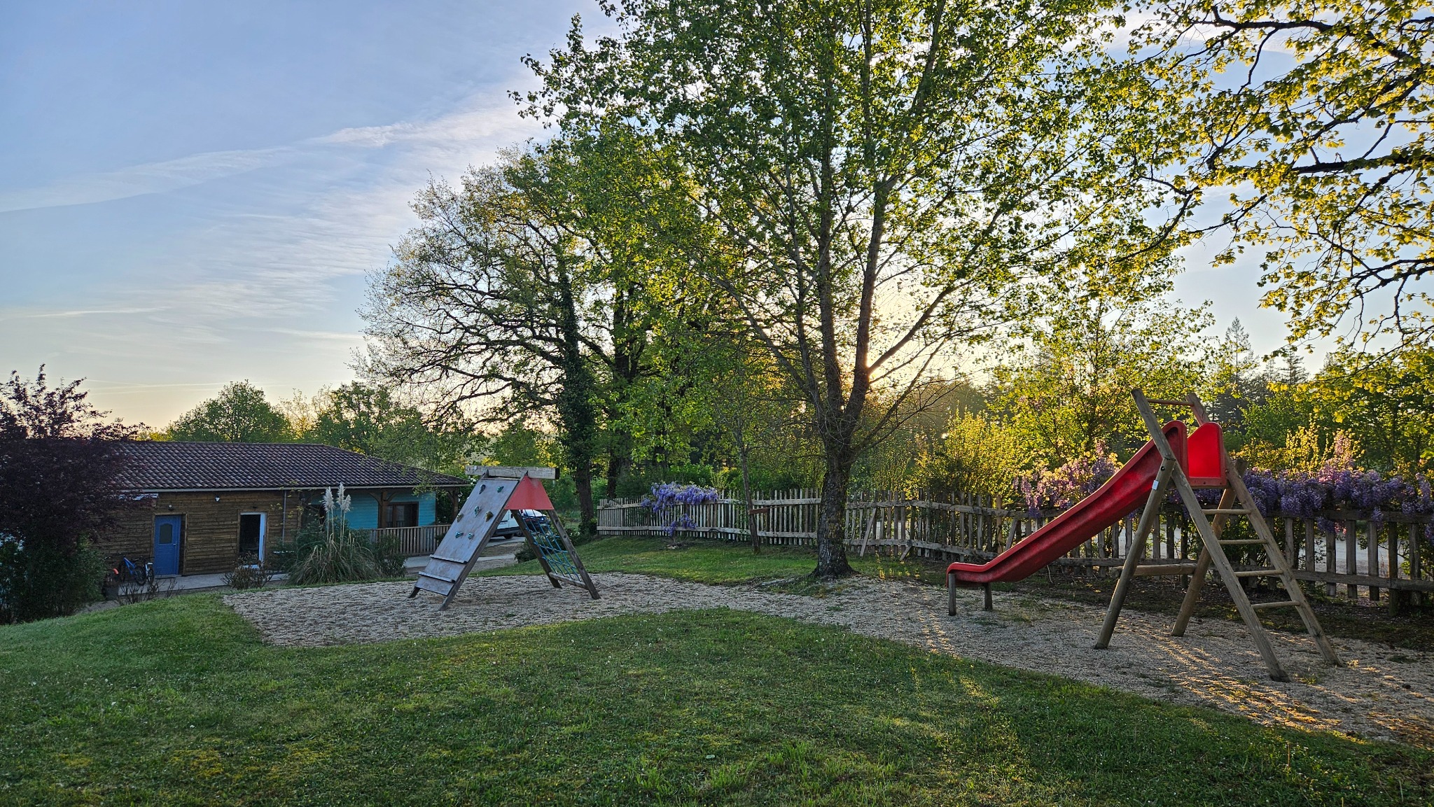 Petite structure à grimper et grand toboggan rouge dans le parc de jeux du Camping Ohana