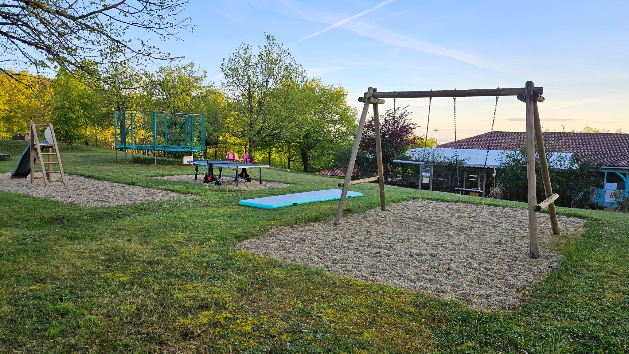 Balançoires, table de ping-pong et trampoline dans le parc de jeux du Camping Ohana