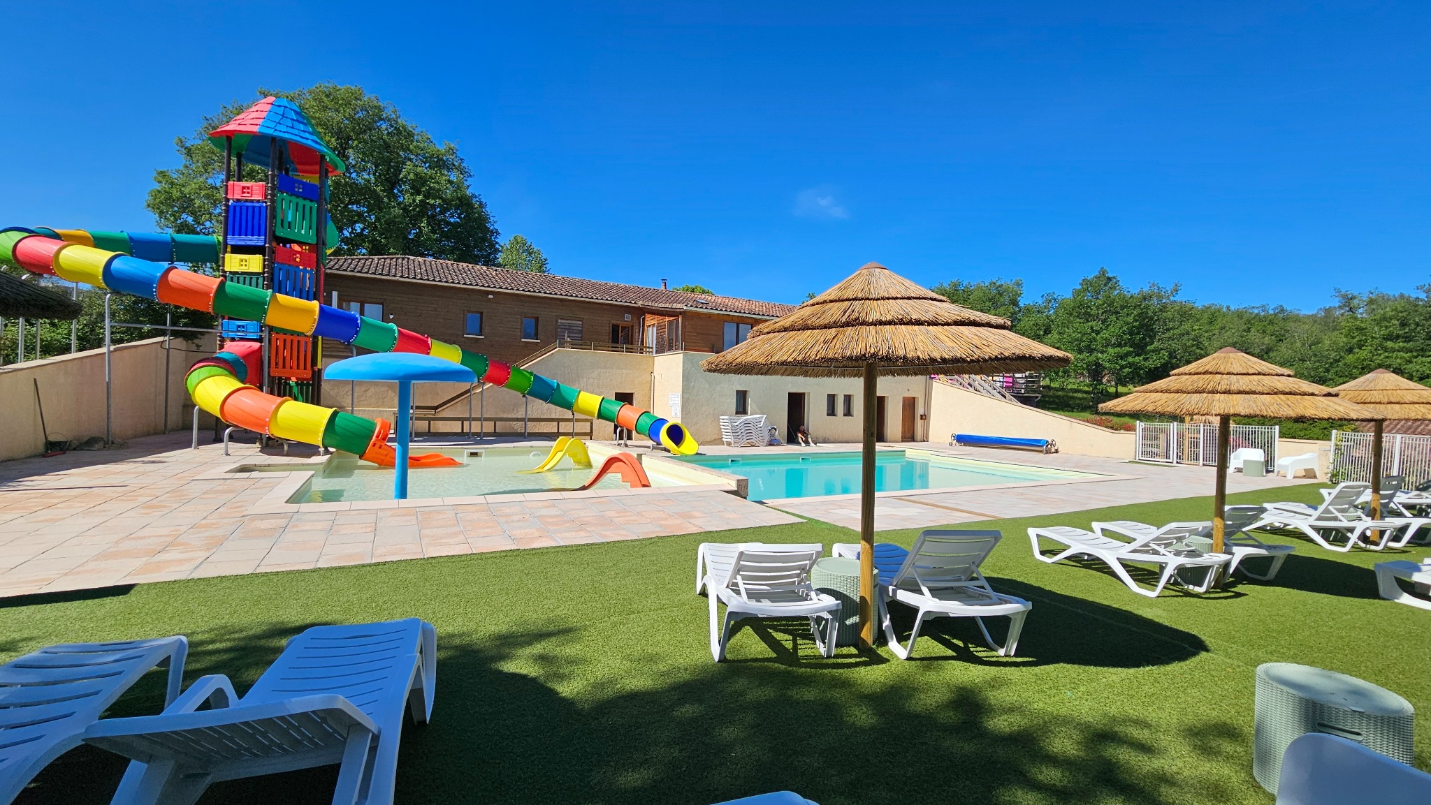 Vue de l’espace piscine du Camping Ohana avec les toboggans, les transats et les parasols