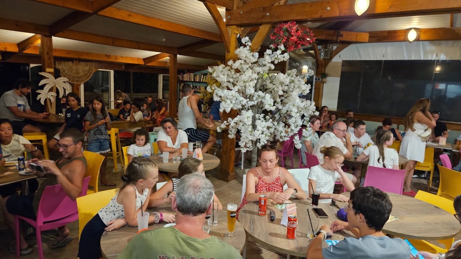 Les vacanciers réunis aux tables de la salle et du bar du Camping Ohana